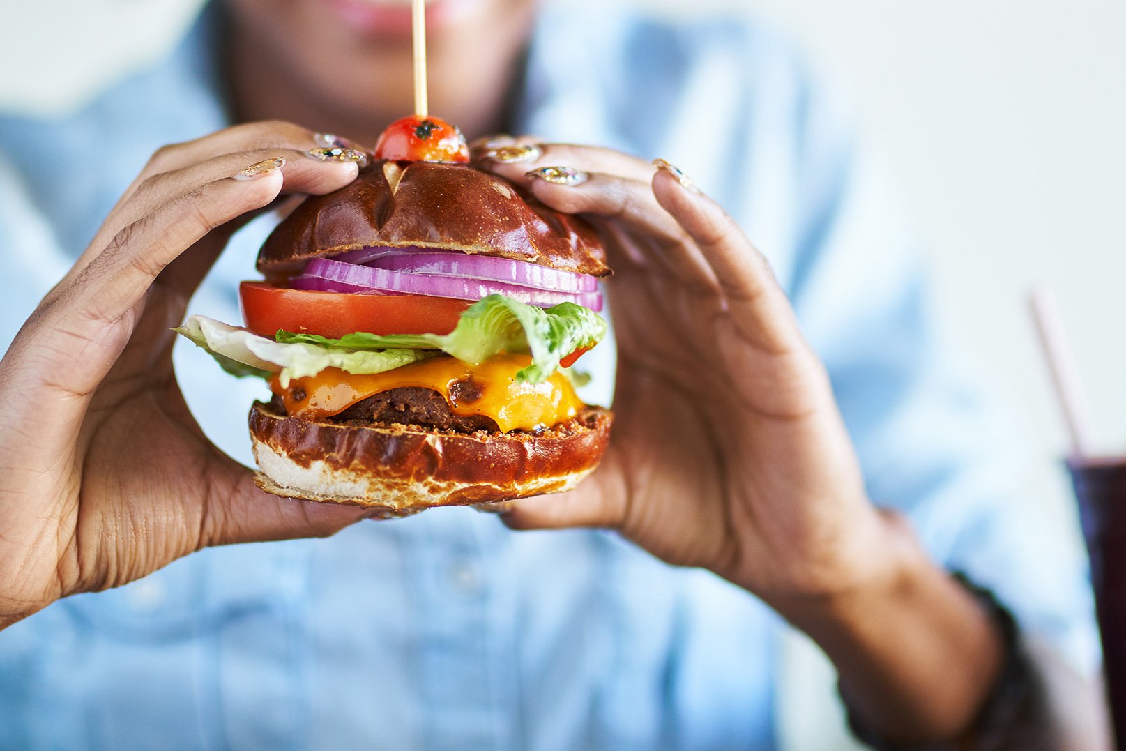 Close up view of a woman holding a delicious plant-based burger in her hands