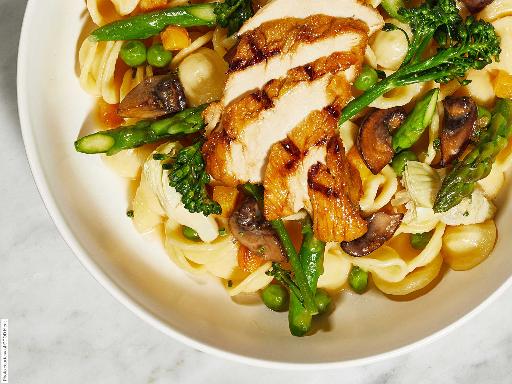 A dish featuring cultivated chicken, pasta, and asparagus.  photo courtesy of good meat.