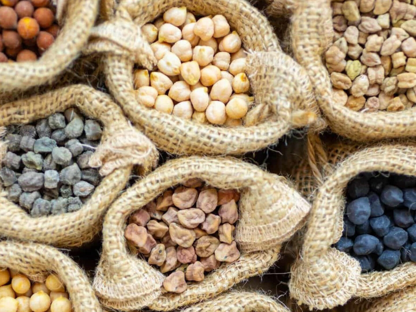 A photo showing burlap sacks of different lentils and legumes; image courtesy of nucicer